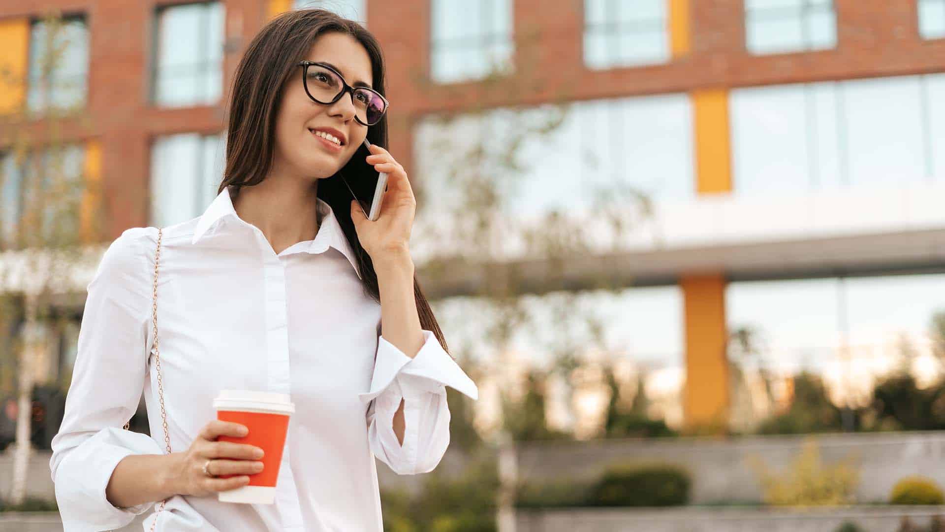 Photo showing a business woman using a mobile device outside conducting a business call
