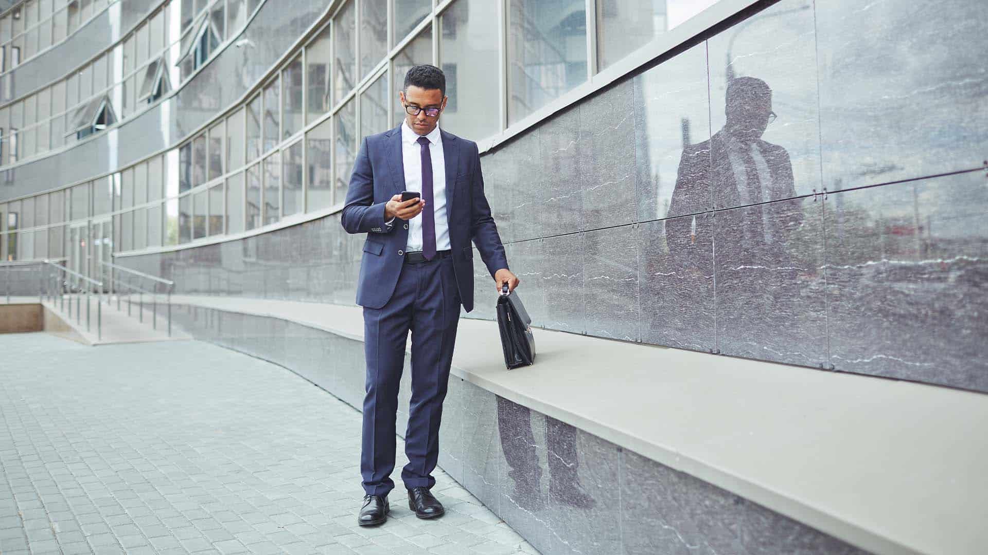 Image showing a business man in a suit checking his mobile device for important work updates